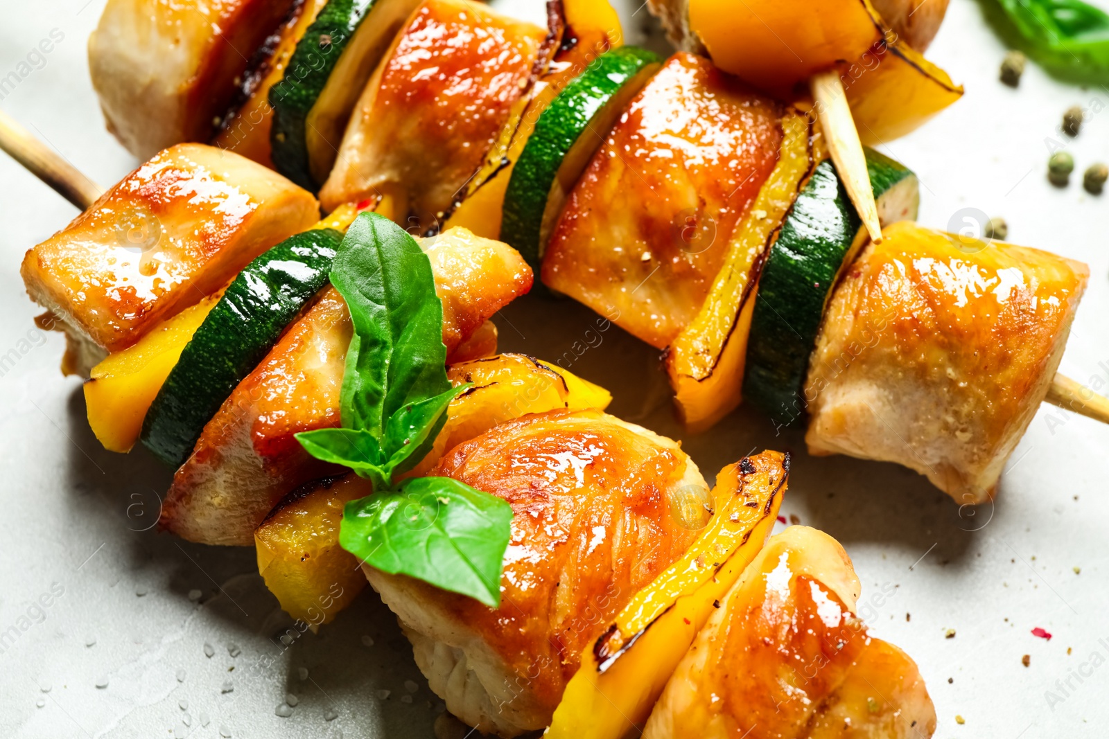 Photo of Delicious chicken shish kebabs with vegetables on grey marble table, closeup