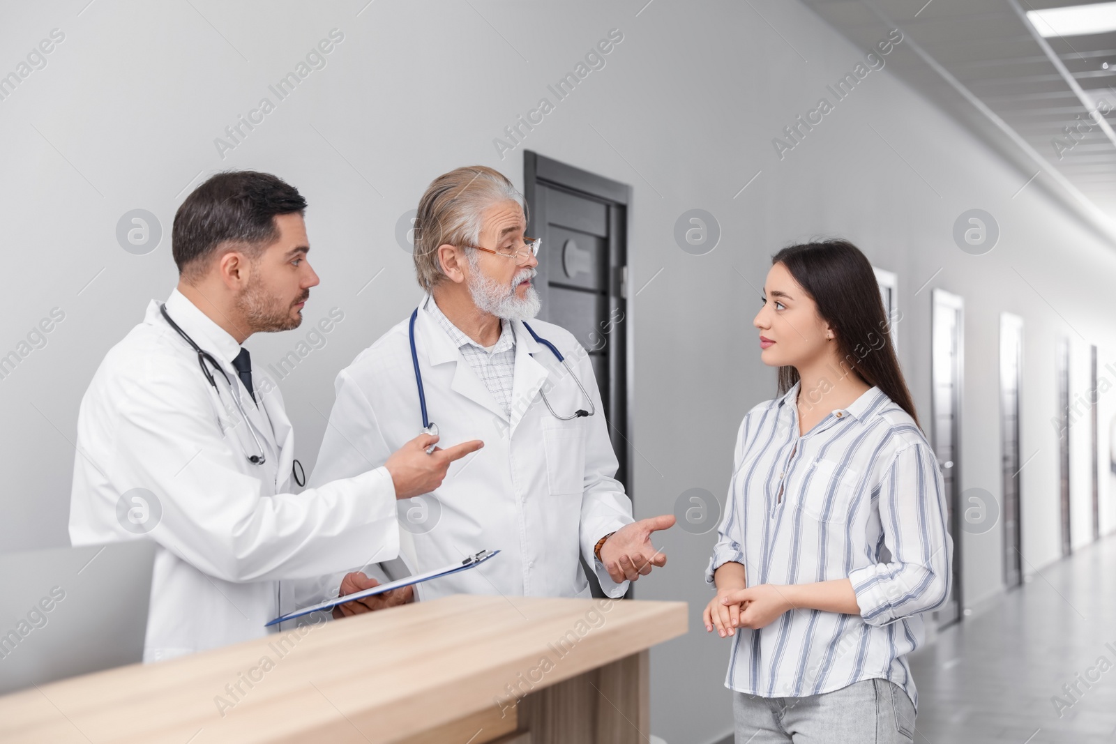 Photo of Doctors consulting patient near reception desk in clinic hall
