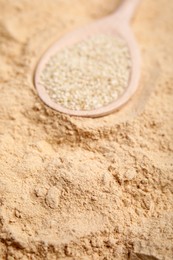Photo of Spoon with sesame seeds on flour, closeup