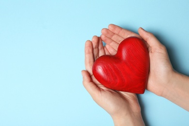 Photo of Woman holding heart on blue background, top view with space for text. Donation concept