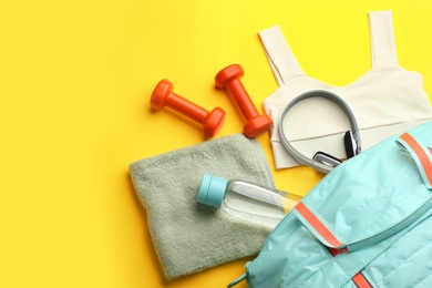 Photo of Flat lay composition with gym bag and sportswear on yellow background