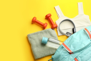 Flat lay composition with gym bag and sportswear on yellow background