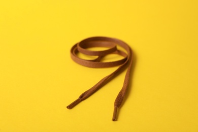 Photo of Long brown shoe lace on yellow background