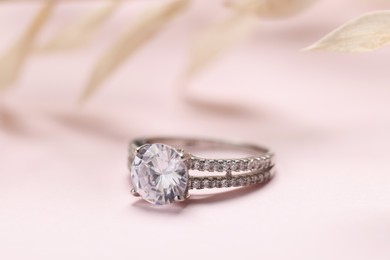 Beautiful ring with gemstones on pale pink background, closeup. Luxury jewelry