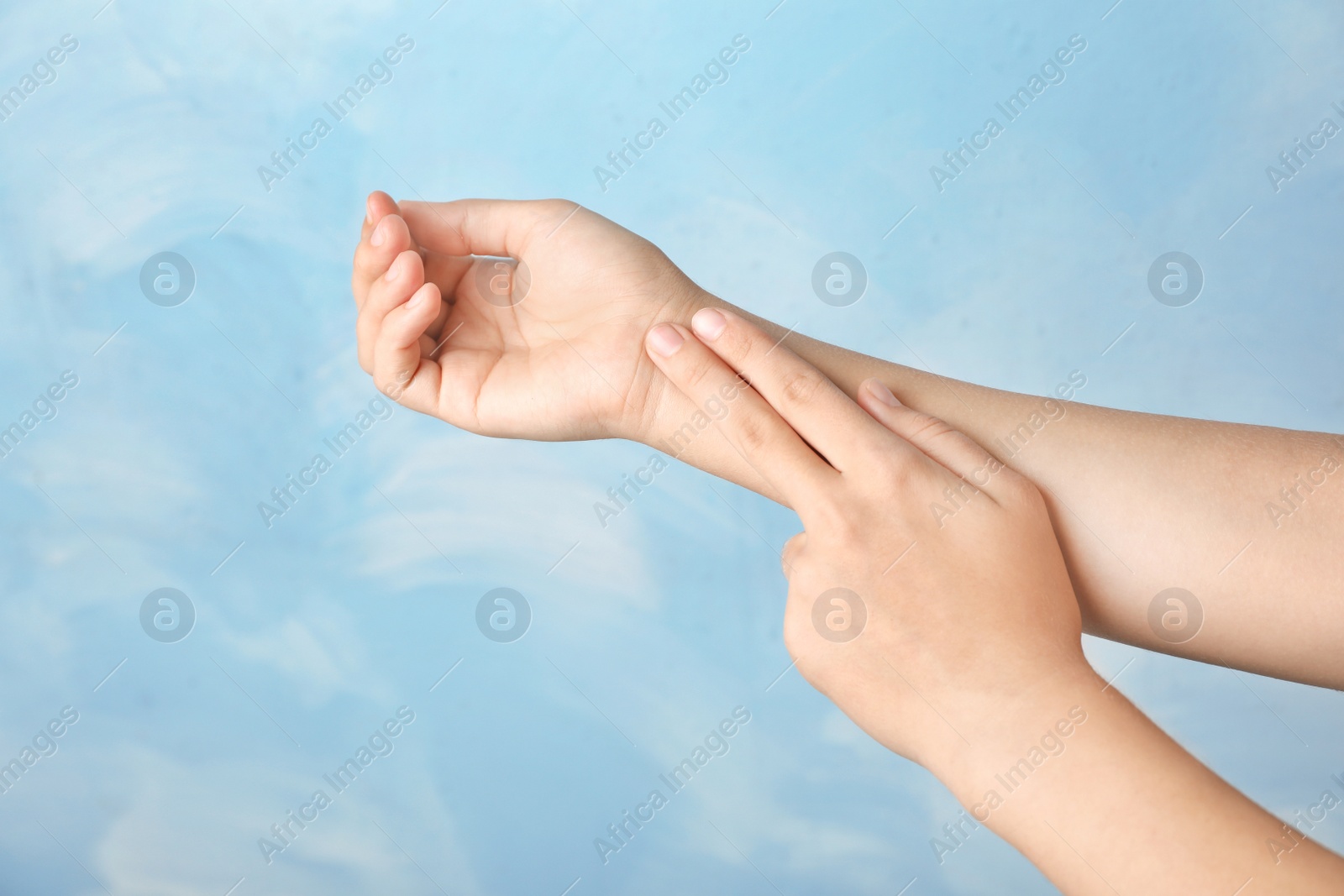 Photo of Woman checking pulse on wrist against color background, closeup