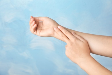 Woman checking pulse on wrist against color background, closeup