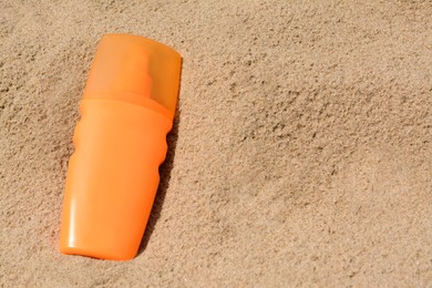 Photo of Bottle with sun protection spray on sandy beach, above view. Space for text
