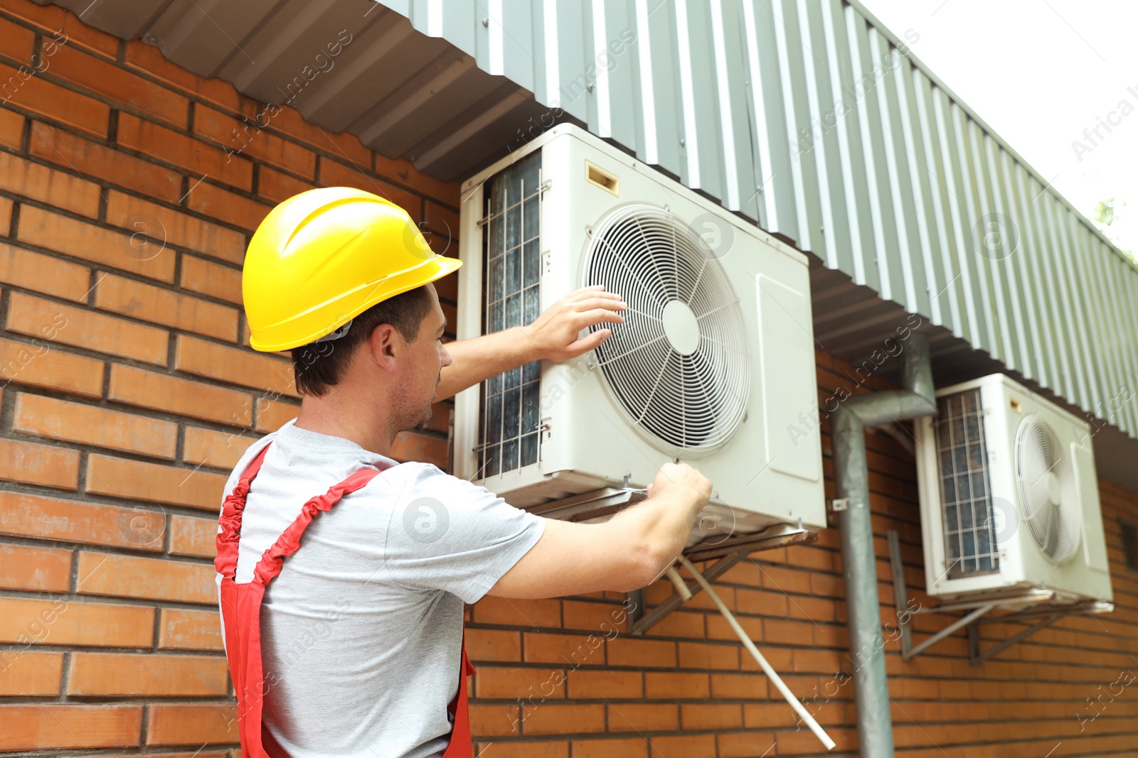 Photo of Male technician fixing air conditioner outdoors