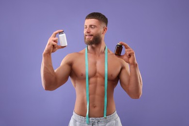 Photo of Athletic young man with measuring tape and bottles of supplements on purple background. Weight loss