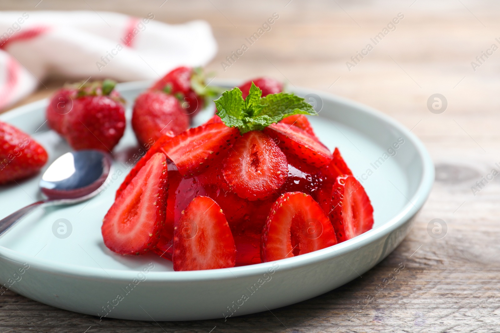 Photo of Delicious fresh red jelly with strawberries and mint on wooden table