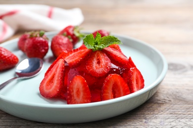 Photo of Delicious fresh red jelly with strawberries and mint on wooden table