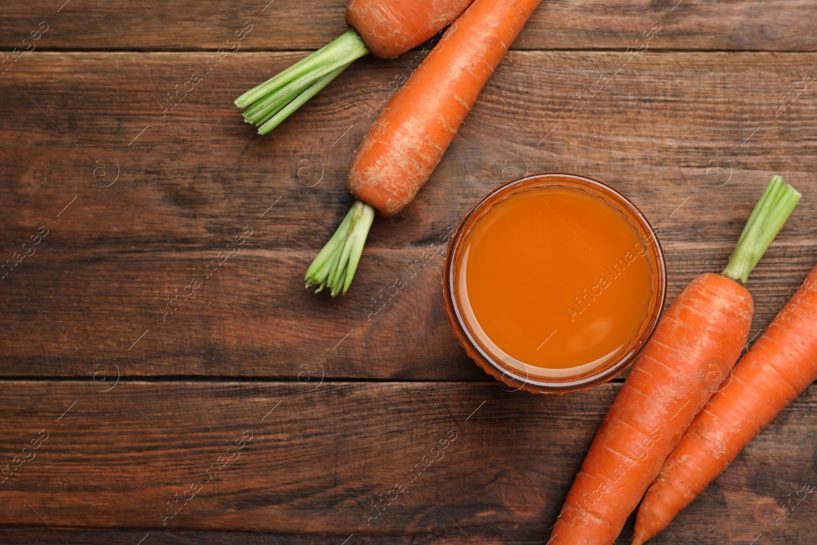 Photo of Flat lay composition with carrots and juice on wooden table, space for text