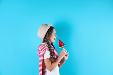 Little girl with candy on color background