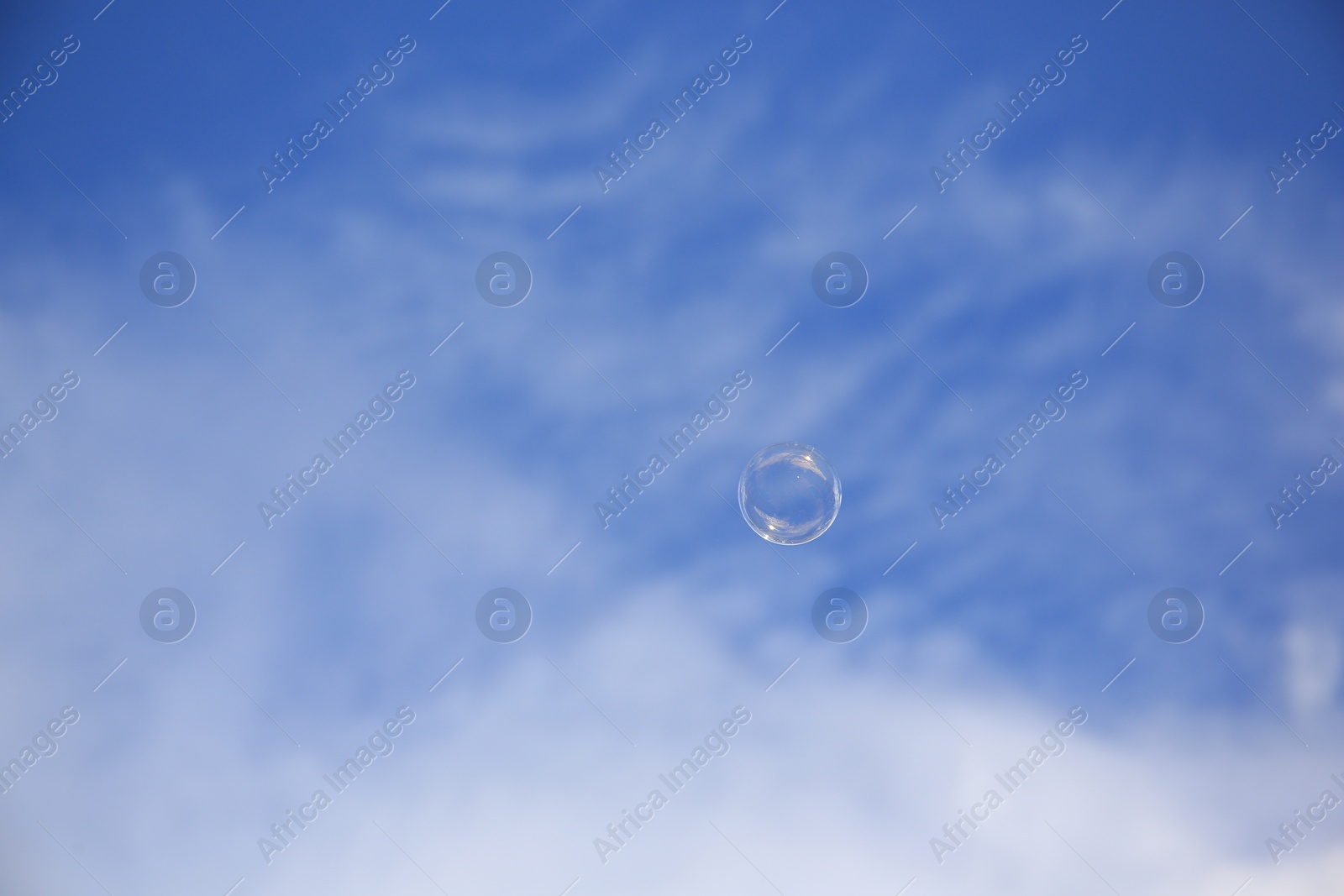 Photo of Beautiful soap bubble floating in blue sky. Space for text