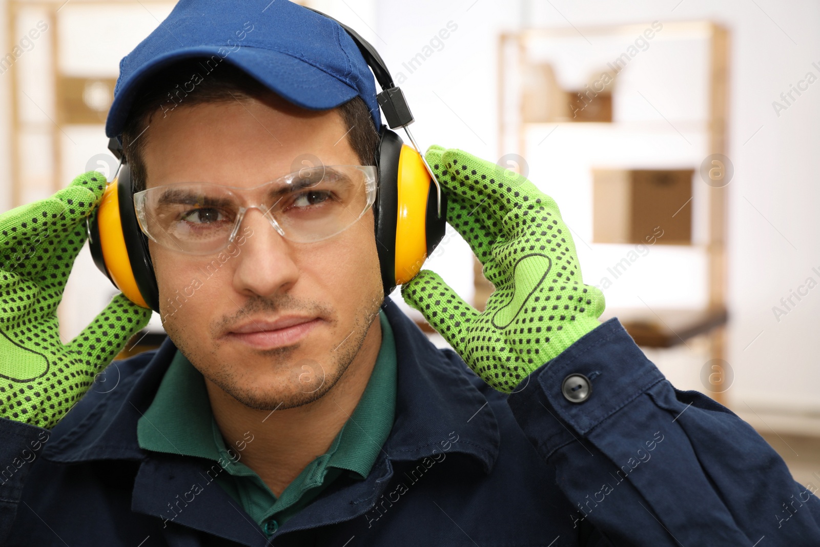 Photo of Worker wearing safety headphones indoors. Hearing protection device