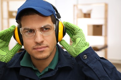 Worker wearing safety headphones indoors. Hearing protection device