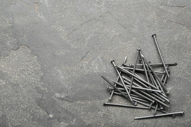 Photo of Pile of metal nails on grey stone background, flat lay. Space for text