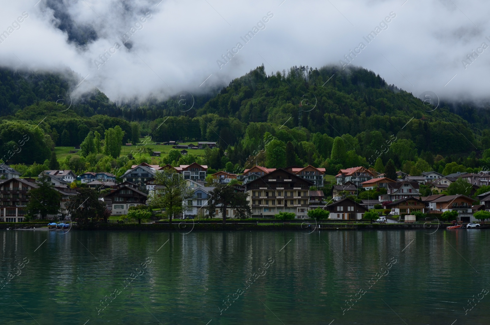 Photo of Picturesque view of beautiful village on lake shore near mountains