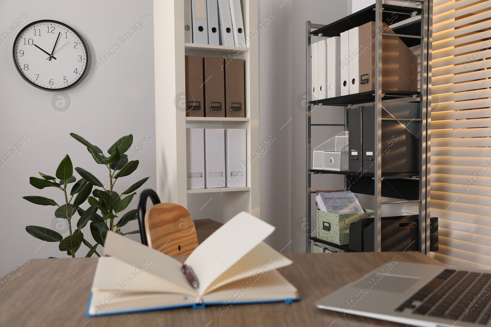 Photo of Stylish office interior with wooden desk, chair, stationery and houseplants