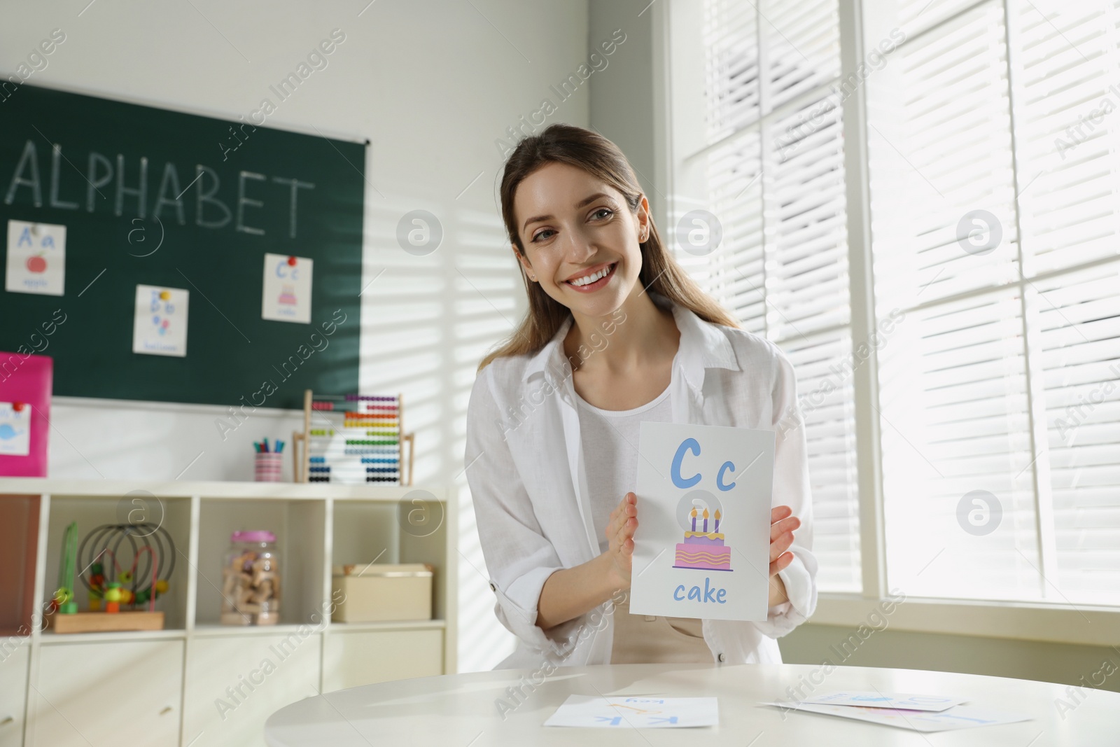 Photo of Happy female English teacher giving lesson in elementary school