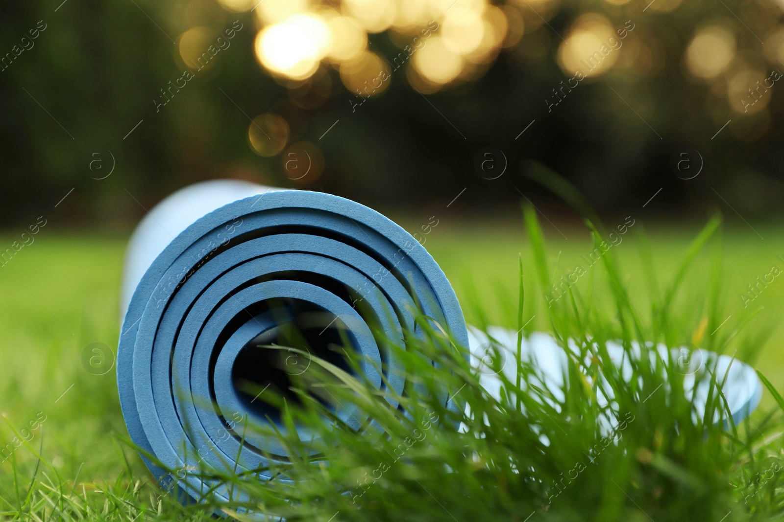 Photo of Bright karemat or fitness mat in fresh green grass outdoors, closeup