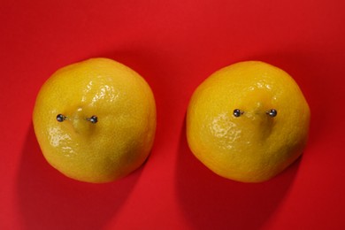 Yellow lemon halves with piercing on red background, flat lay