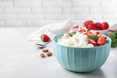 Fresh cottage cheese with strawberry and almond in bowl on light marble table. Space for text