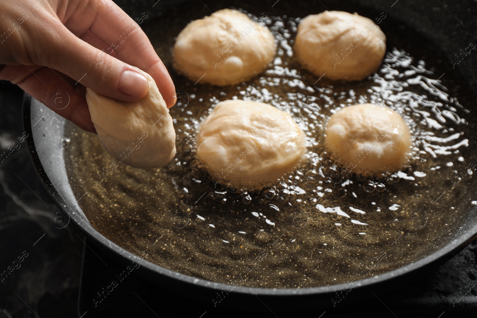 Photo of Woman cooking delicious donuts in oil, closeup