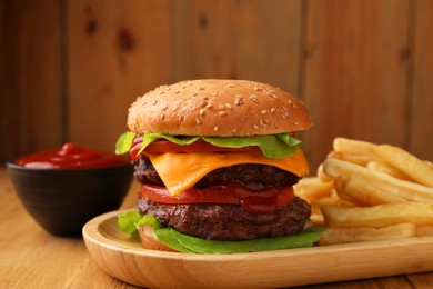Tasty cheeseburger with patties, sauce and French fries on wooden table, closeup