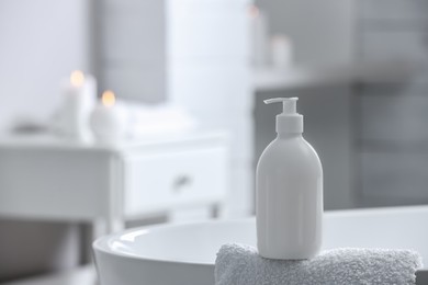 Photo of Bottle of bubble bath and towel on tub in bathroom, space for text