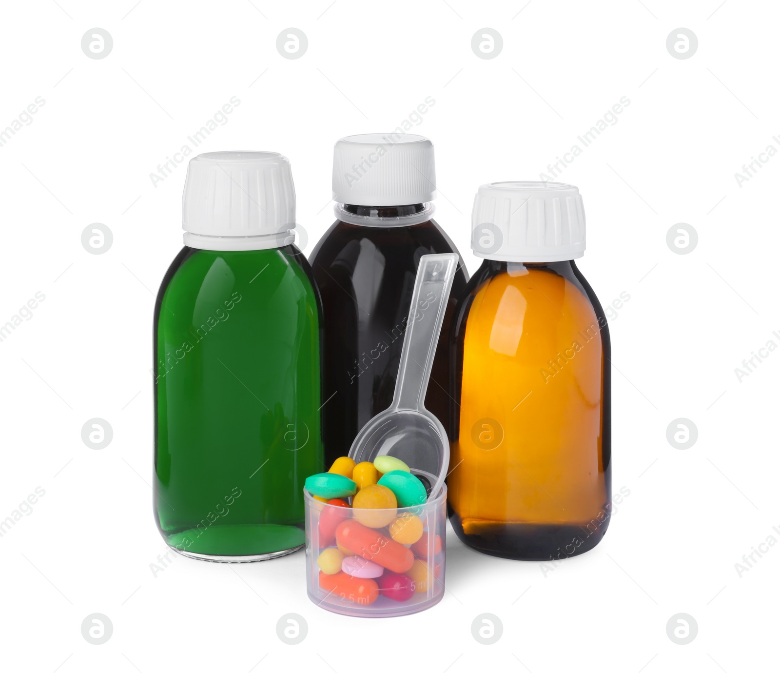 Photo of Bottles of syrups, measuring cup, plastic spoon with pills on white background. Cough and cold medicine