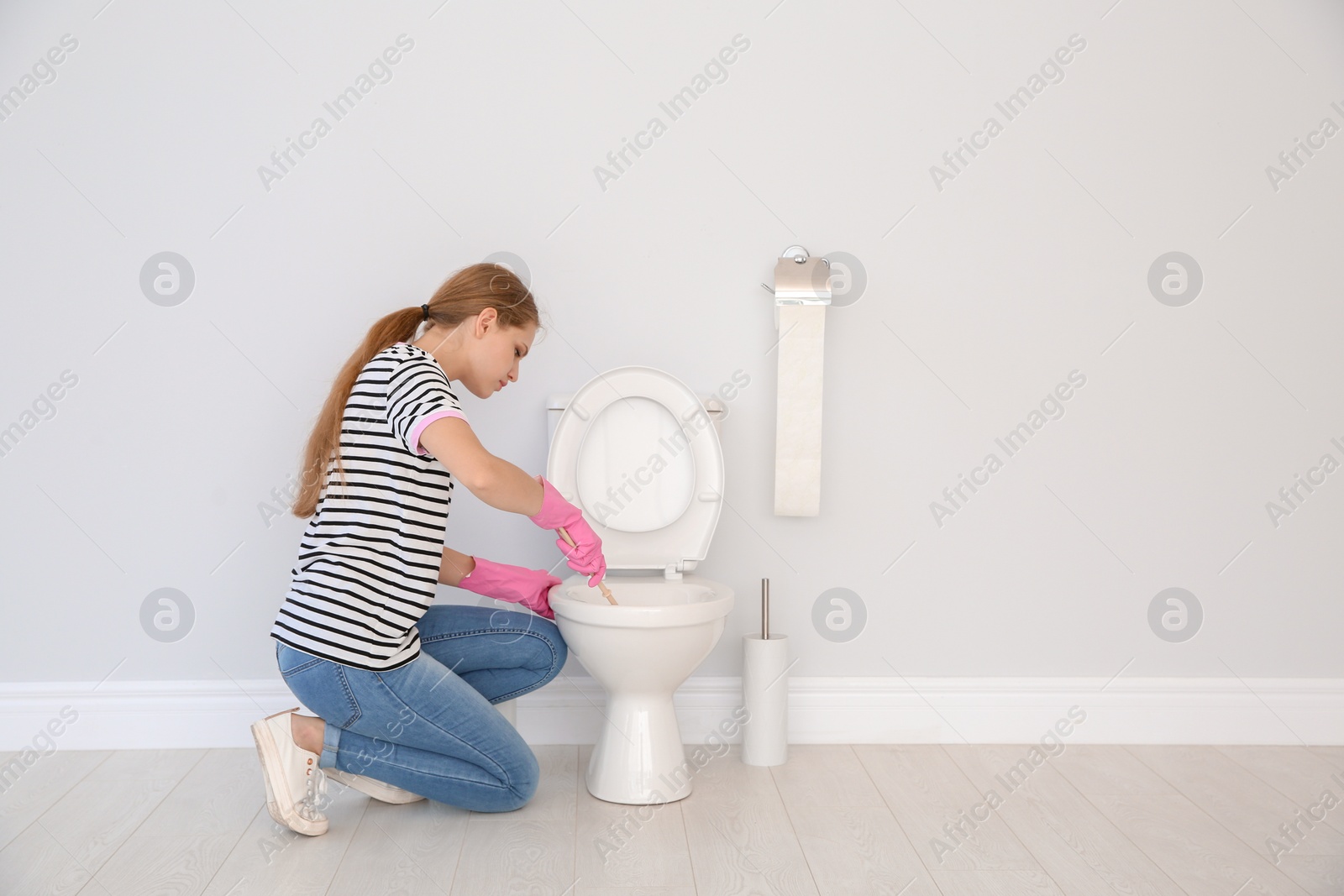 Photo of Woman cleaning toilet bowl in bathroom