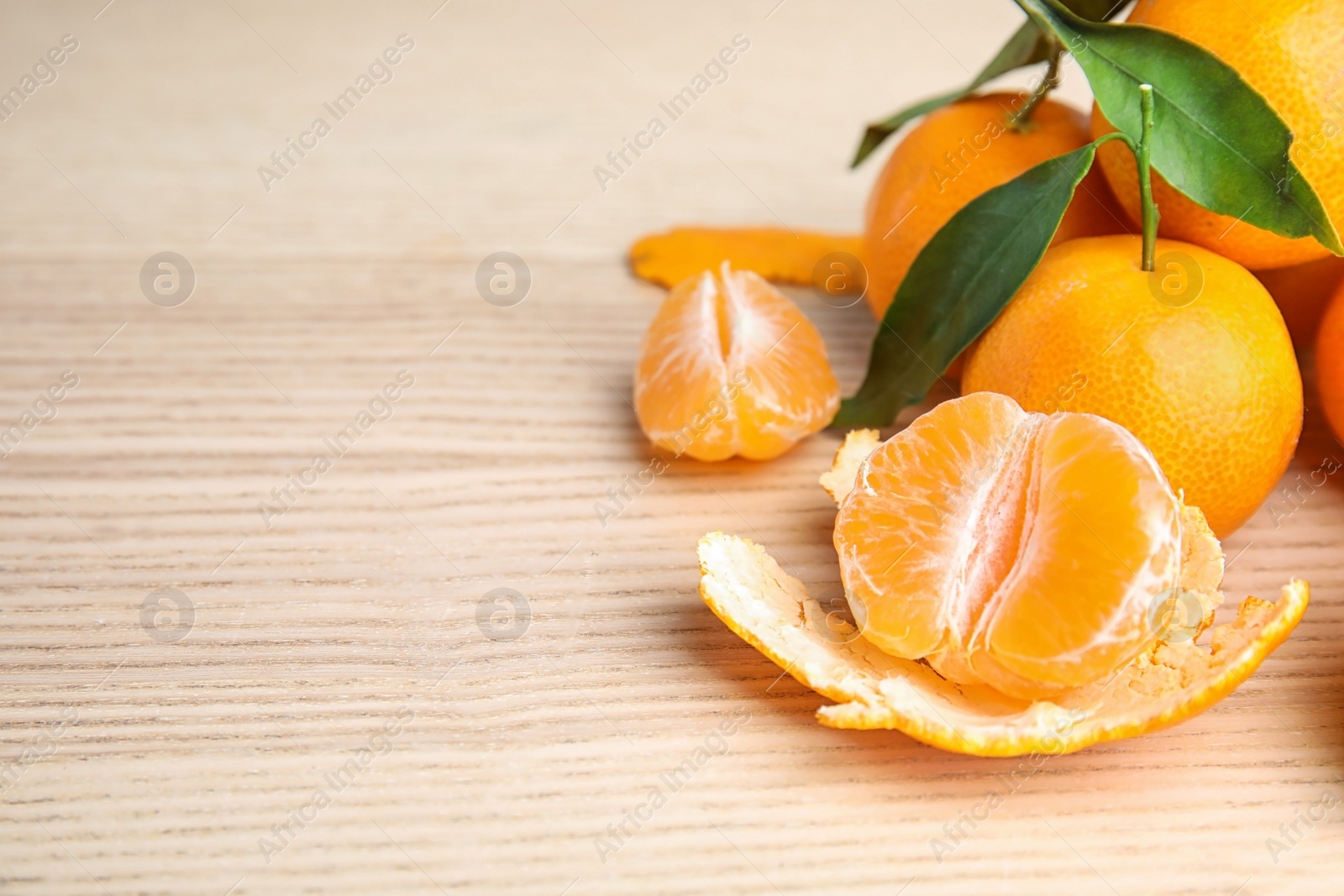 Photo of Fresh ripe tangerines with green leaves on table. Space for text