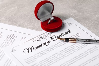 Photo of Marriage contract, fountain pen and ring with gemstone on grey table