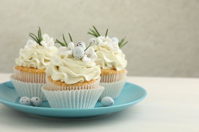 Tasty Easter cupcakes with vanilla cream on light wooden table, space for text