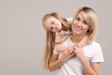 Family portrait of happy mother and daughter on grey background. Space for text