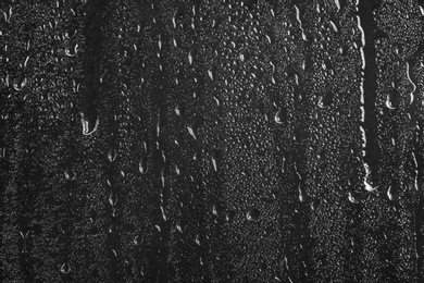 Photo of Glass with rain drops against dark background