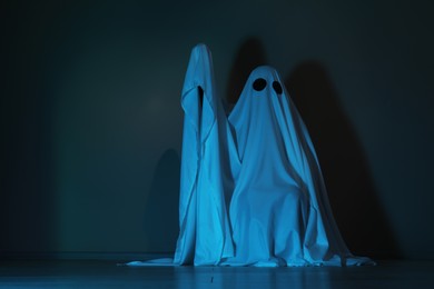 Creepy ghost. Woman covered with sheet in color light, space for text