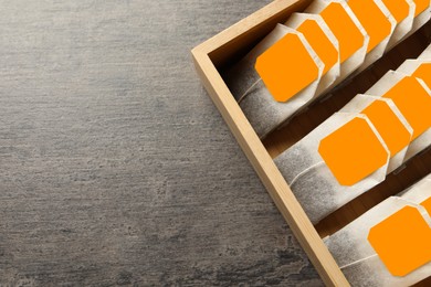 Photo of Wooden box with paper tea bags on dark grey table, top view. Space for text