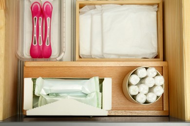 Storage of different feminine hygiene products in wooden drawer, top view