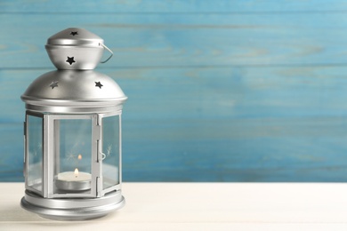Photo of Beautiful decorative Christmas lantern with burning candle on white wooden table. Space for text