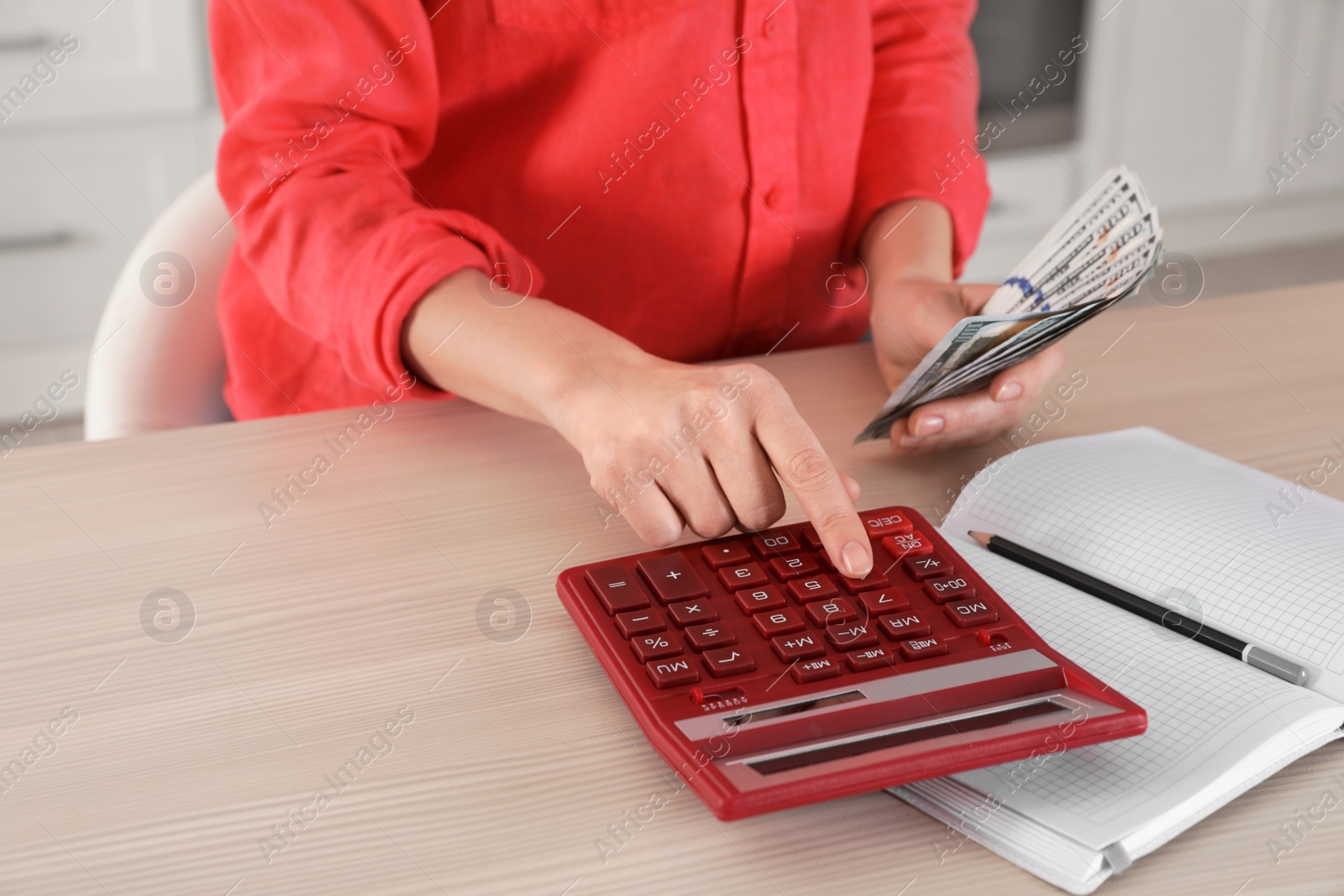 Photo of Woman counting money with calculator at table, closeup