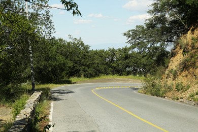 Empty asphalted road with marking near trees outdoors