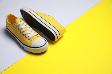 Pair of yellow classic old school sneakers on color background, space for text