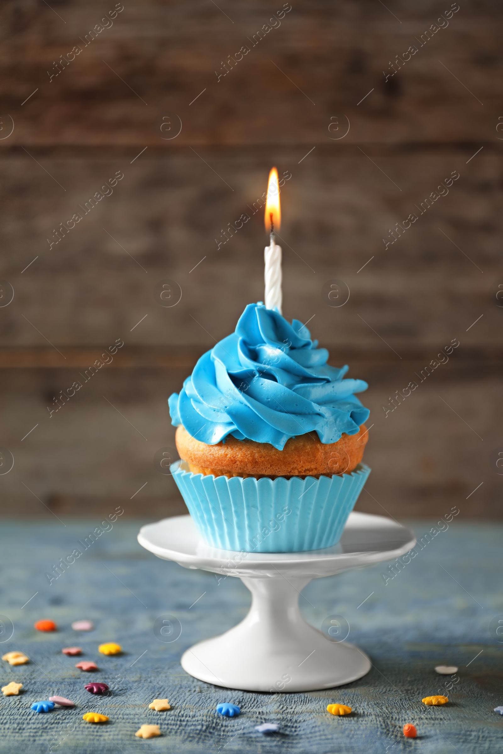 Photo of Delicious birthday cupcake with candle on table