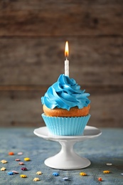 Photo of Delicious birthday cupcake with candle on table