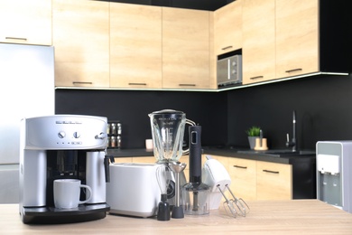 Photo of Modern domestic appliances on wooden table in kitchen. Space for text