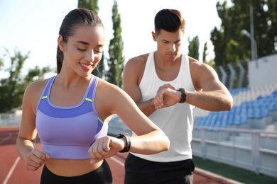 Photo of Couple with fitness trackers running at stadium