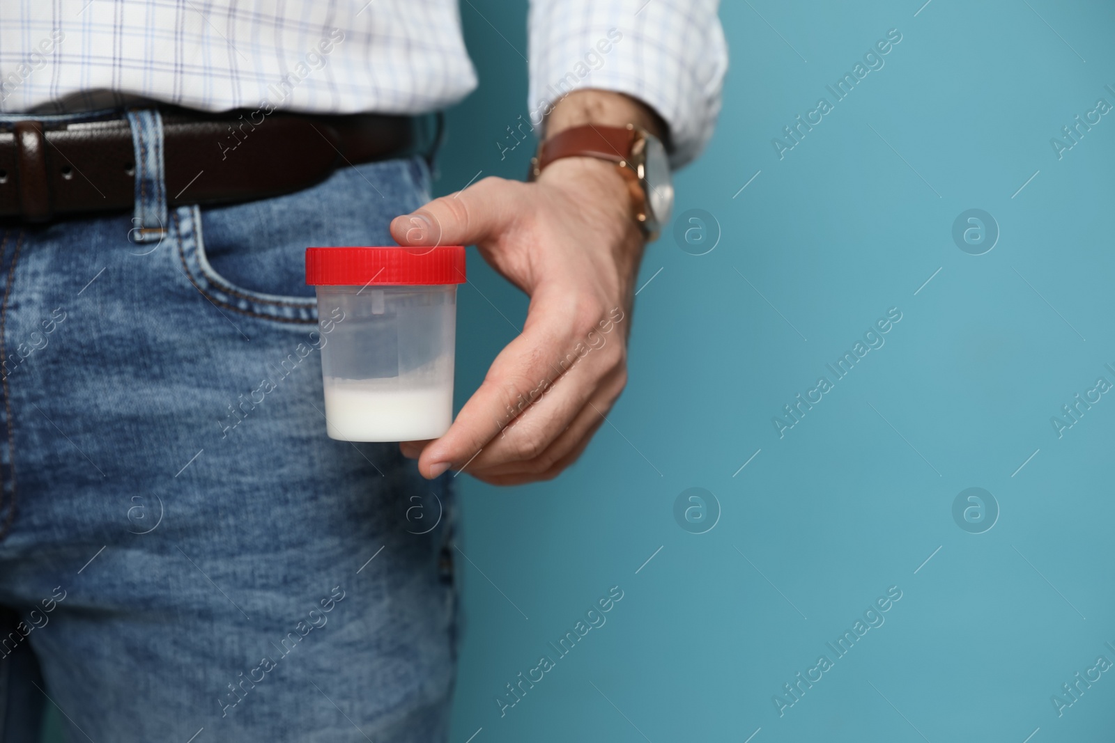 Photo of Donor holding container with sperm on turquoise background, closeup. Space for text