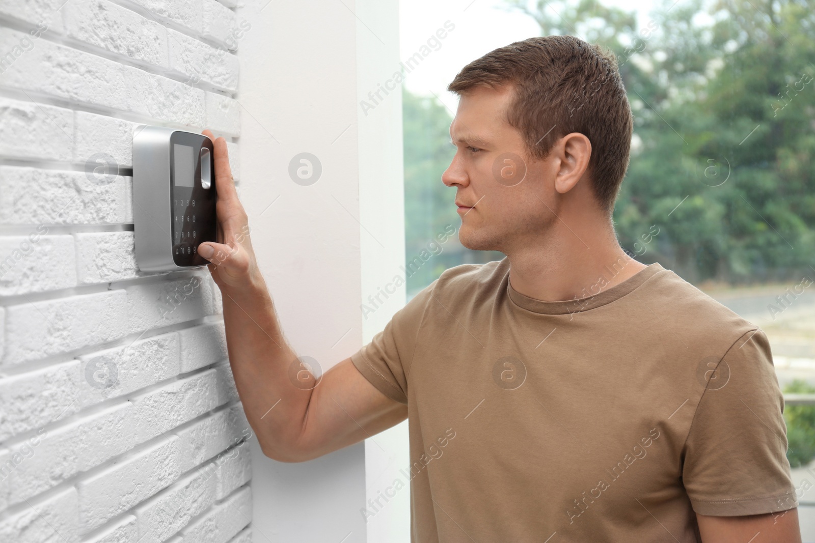 Photo of Handsome man using security alarm system indoors